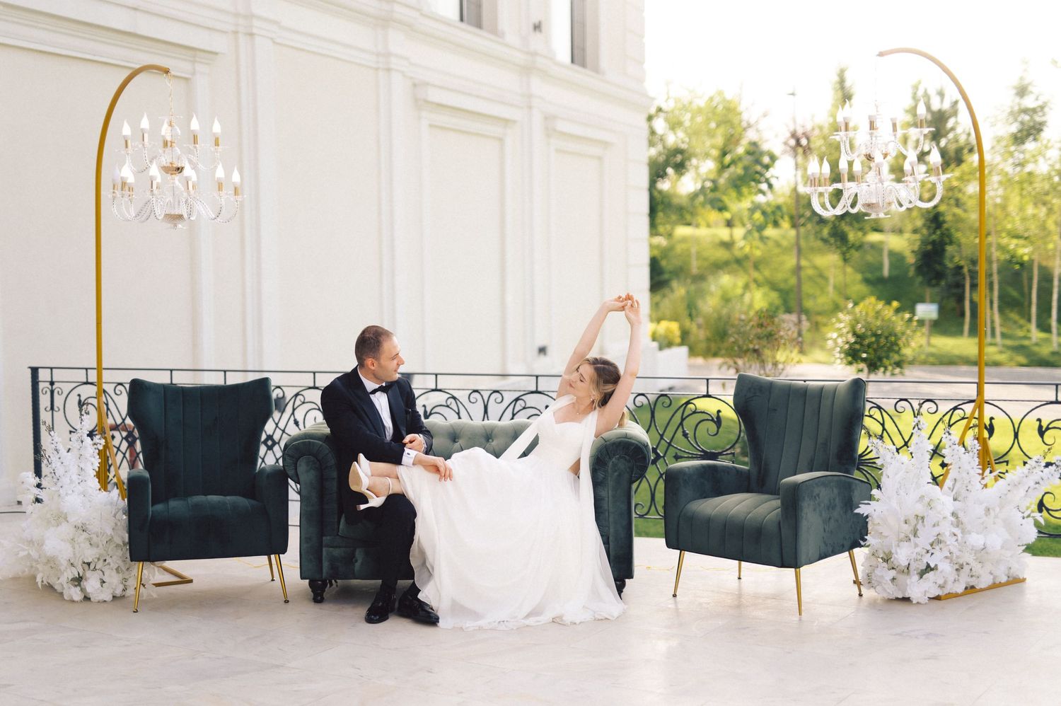 A bride and groom share intimate moments in a luxurious white room with elegant decor and bright natural lighting.