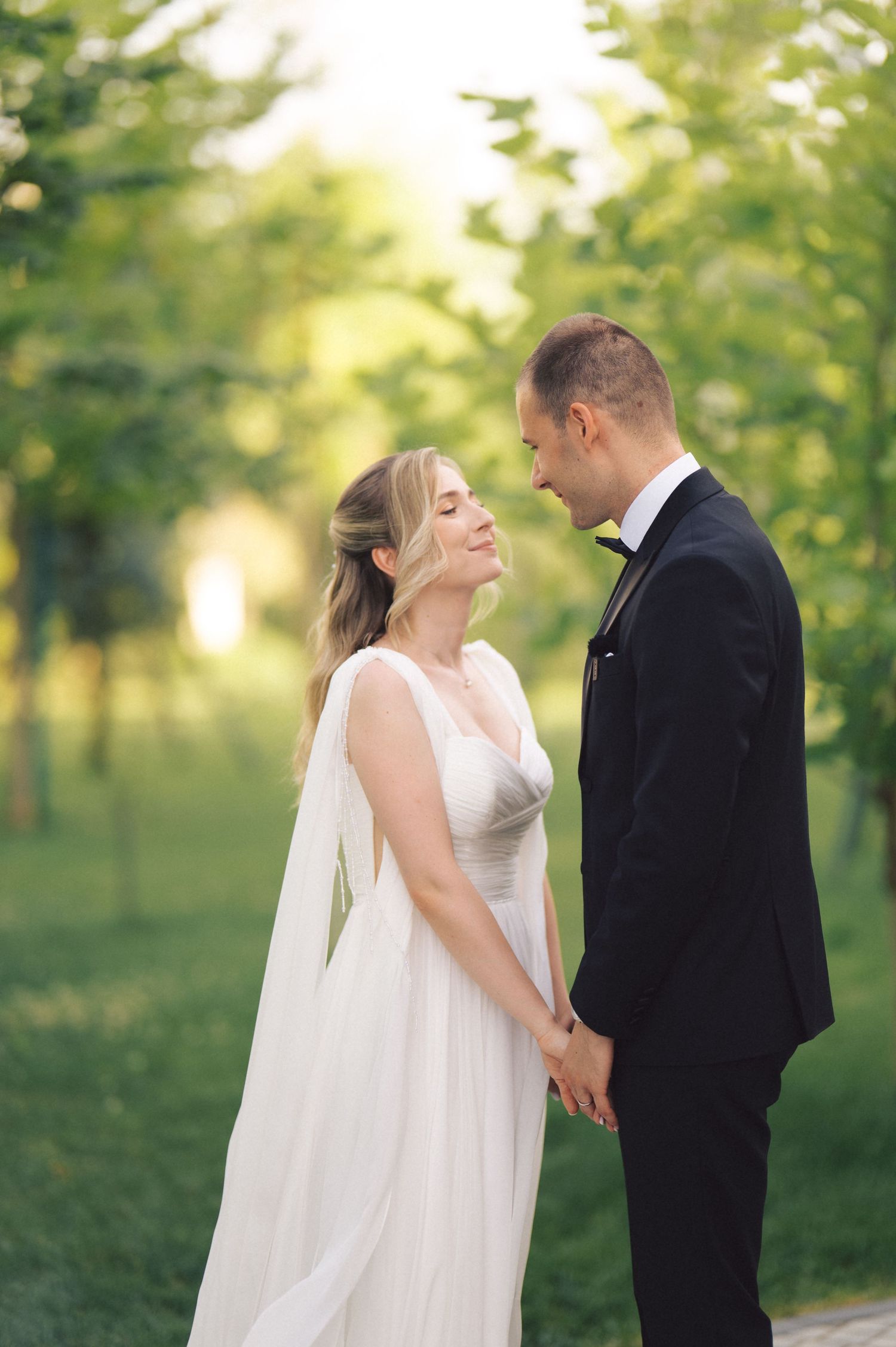 Romantic couple share an intimate moment in a sun-dappled garden setting during their outdoor wedding ceremony.