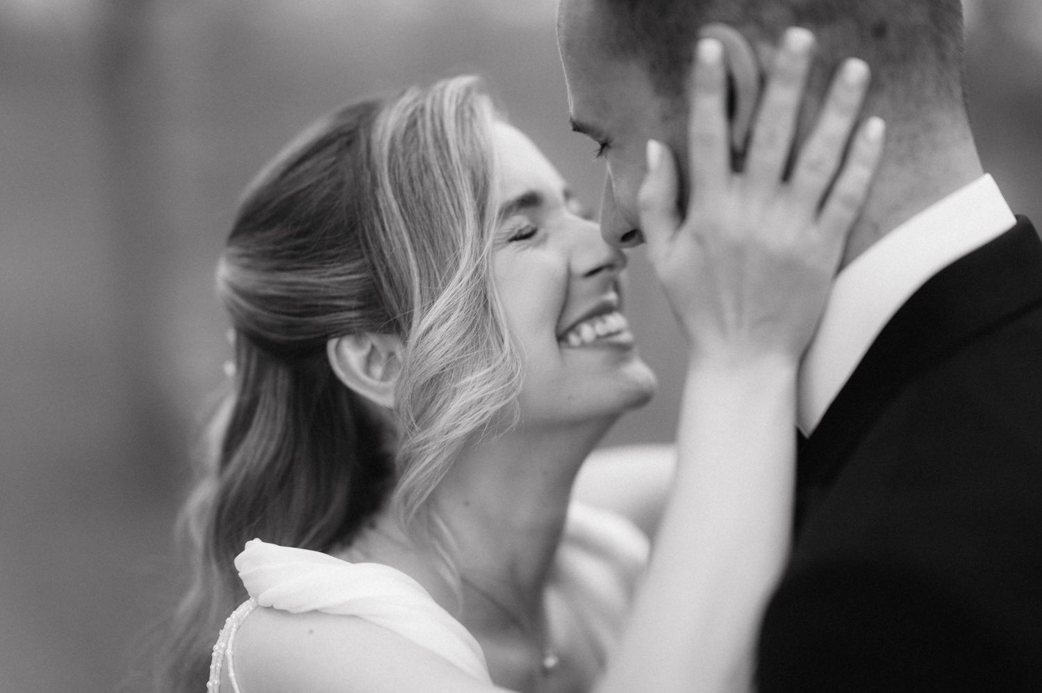 An intimate black and white portrait captures a joyful emotional moment between newlyweds.