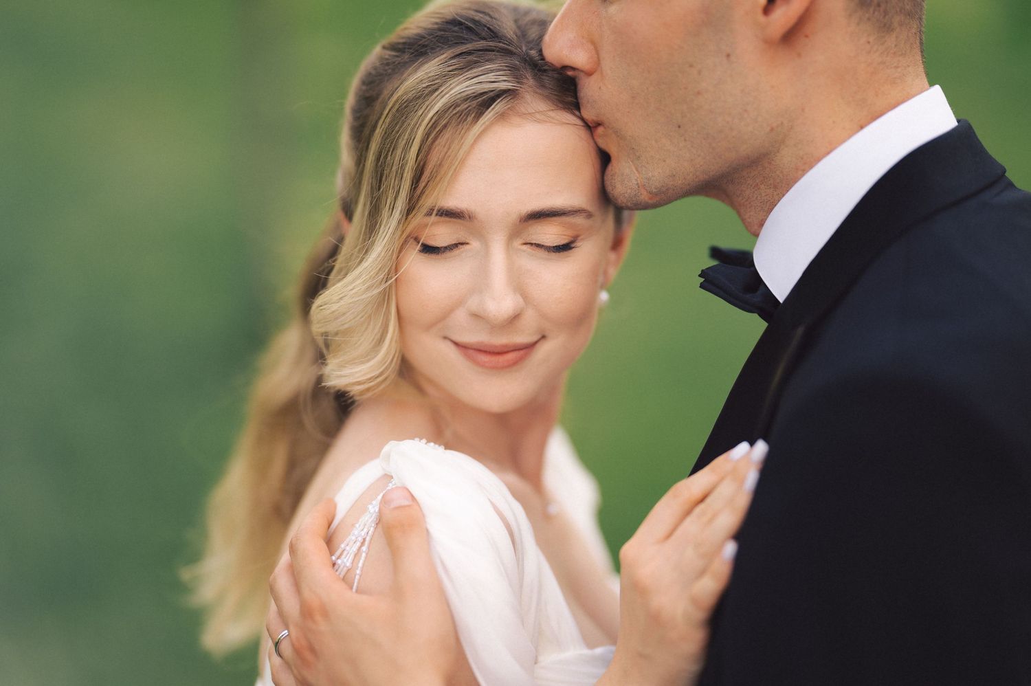 Romantic wedding couple shares intimate moment in outdoor garden setting with lush greenery.