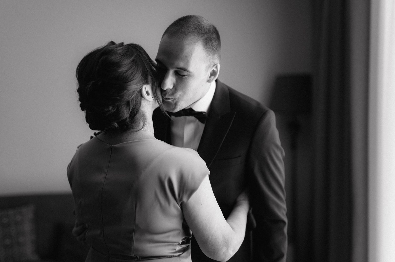 A romantic black and white photo of a couple in elegant attire sharing an intimate moment.