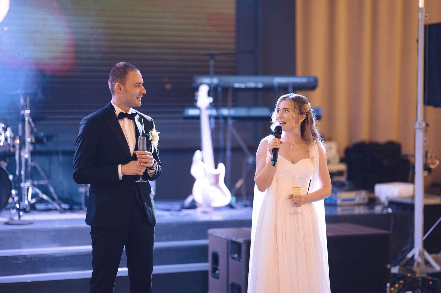 A bride and groom share their first dance performance on stage at an elegant wedding reception.
