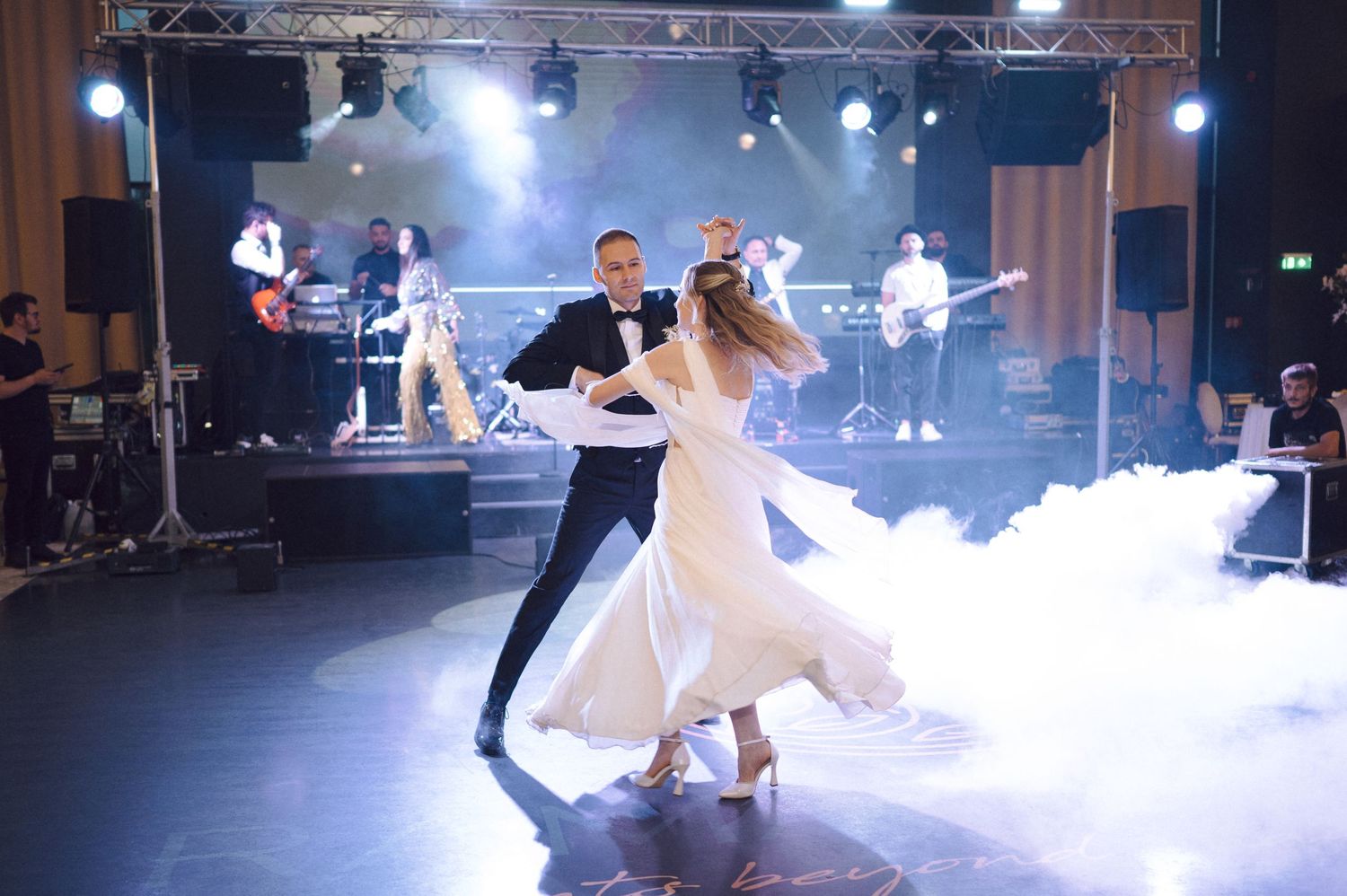 Newlyweds perform their first dance surrounded by atmospheric fog and dramatic lighting at their wedding reception.