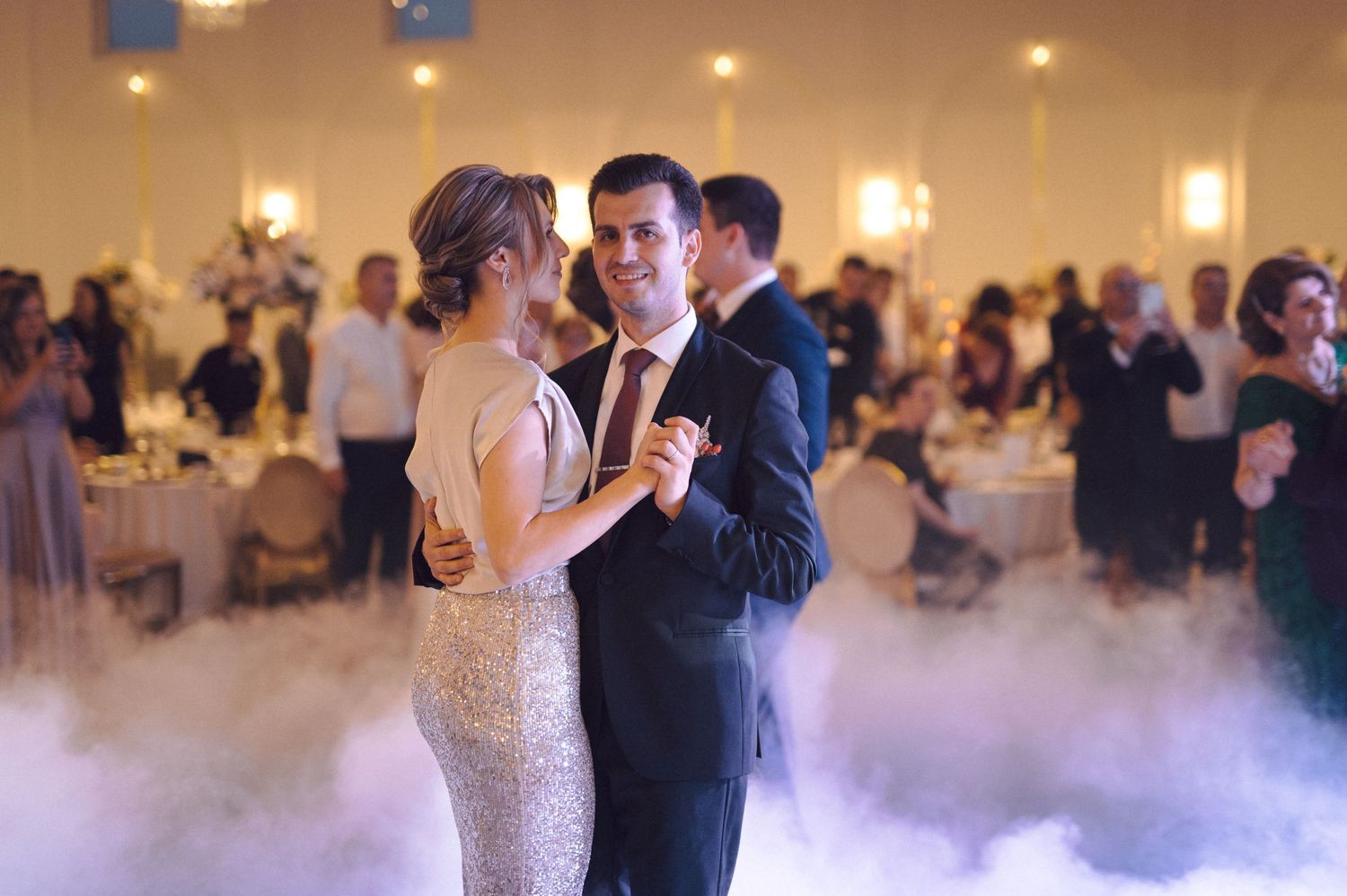Couples dancing at an elegant wedding reception on a misty dance floor with soft lighting and romantic atmosphere.