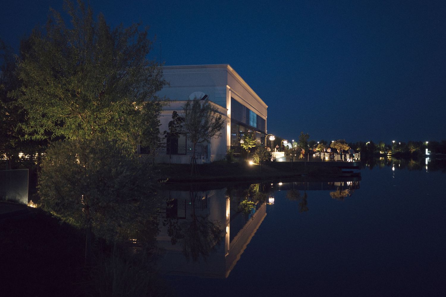 Night views of illuminated basketball courts with backboards and hoops at an outdoor city park.