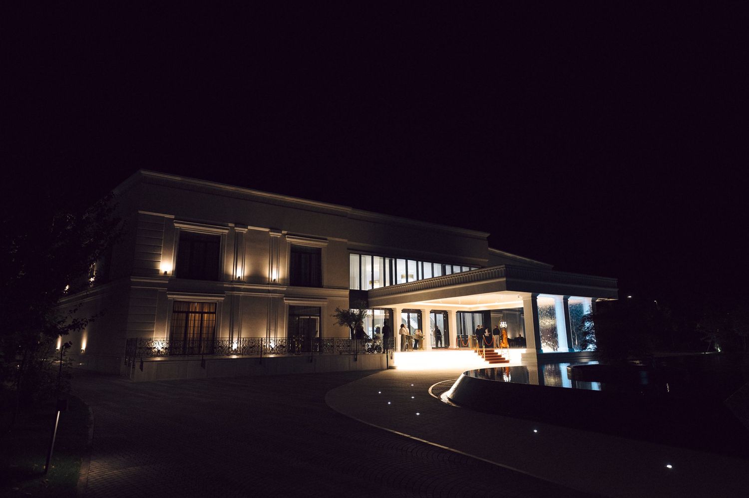 Side view of a modern illuminated building at night showing multiple entrances and exterior lighting.