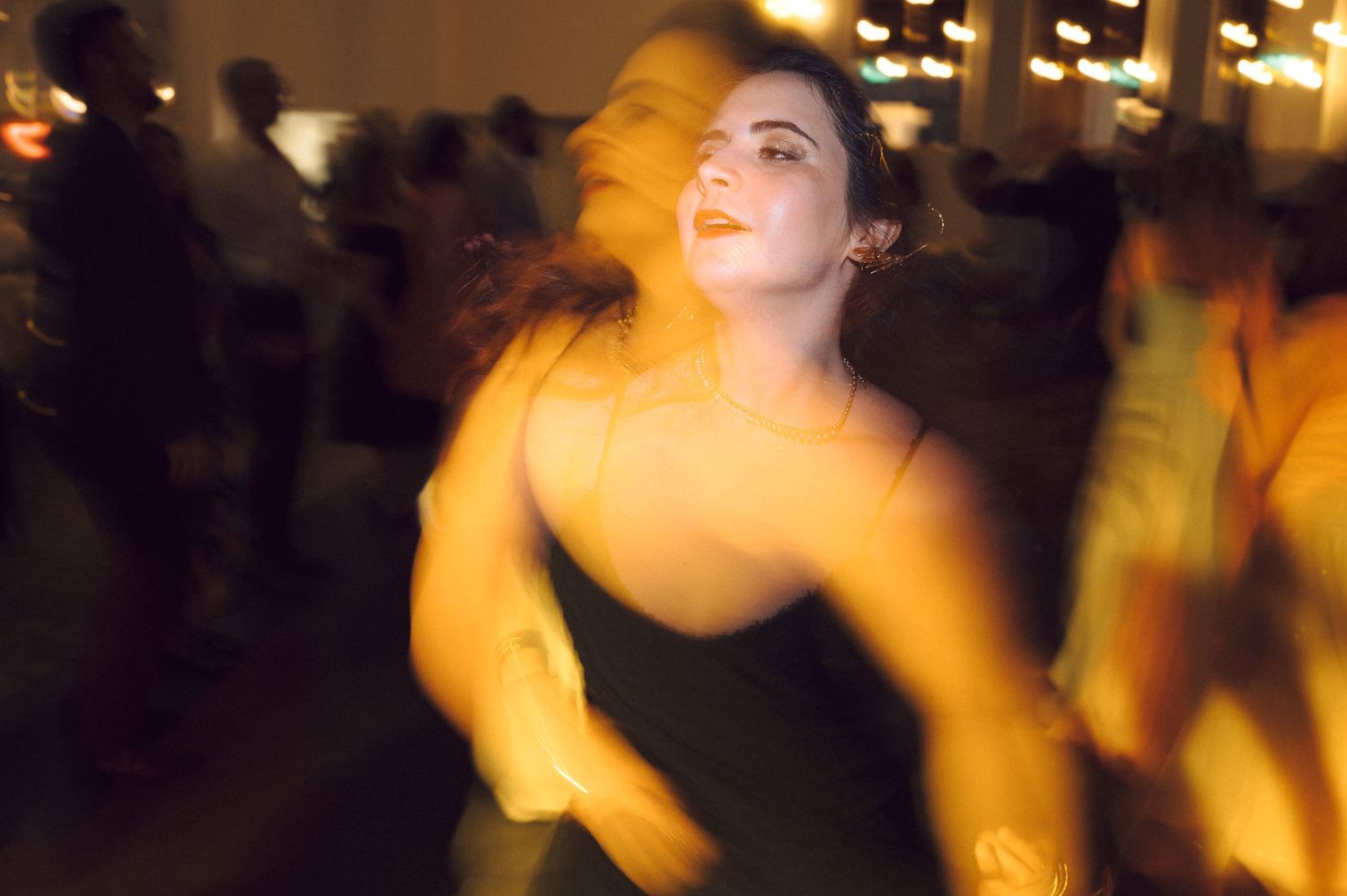 A person dances with motion blur in a dimly lit room with warm golden lighting casting atmospheric shadows.