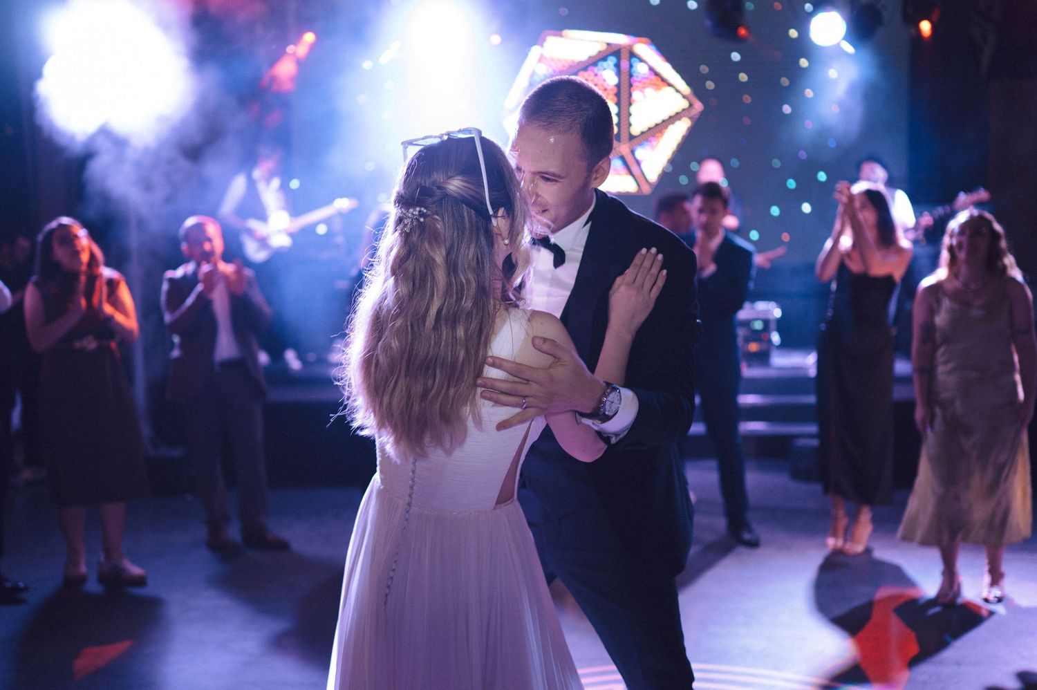 A romantic first dance at a wedding reception with soft lighting and guests watching in the background.