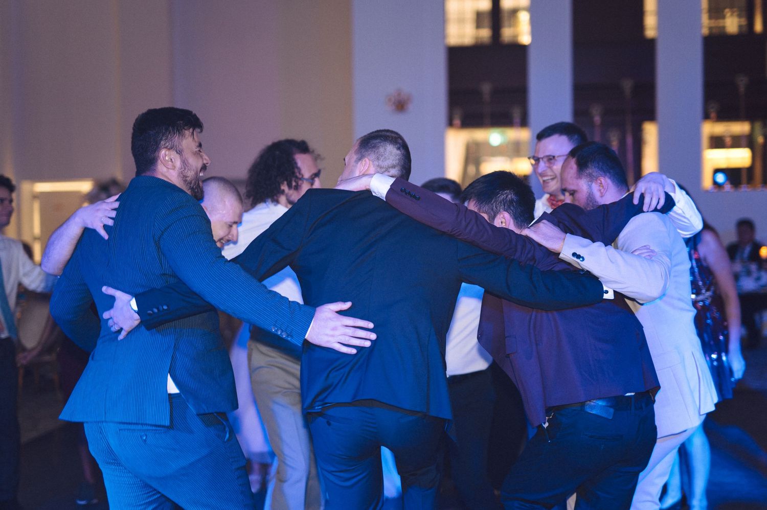 Several couples dancing together in a ballroom scene with blue lighting and formal attire.