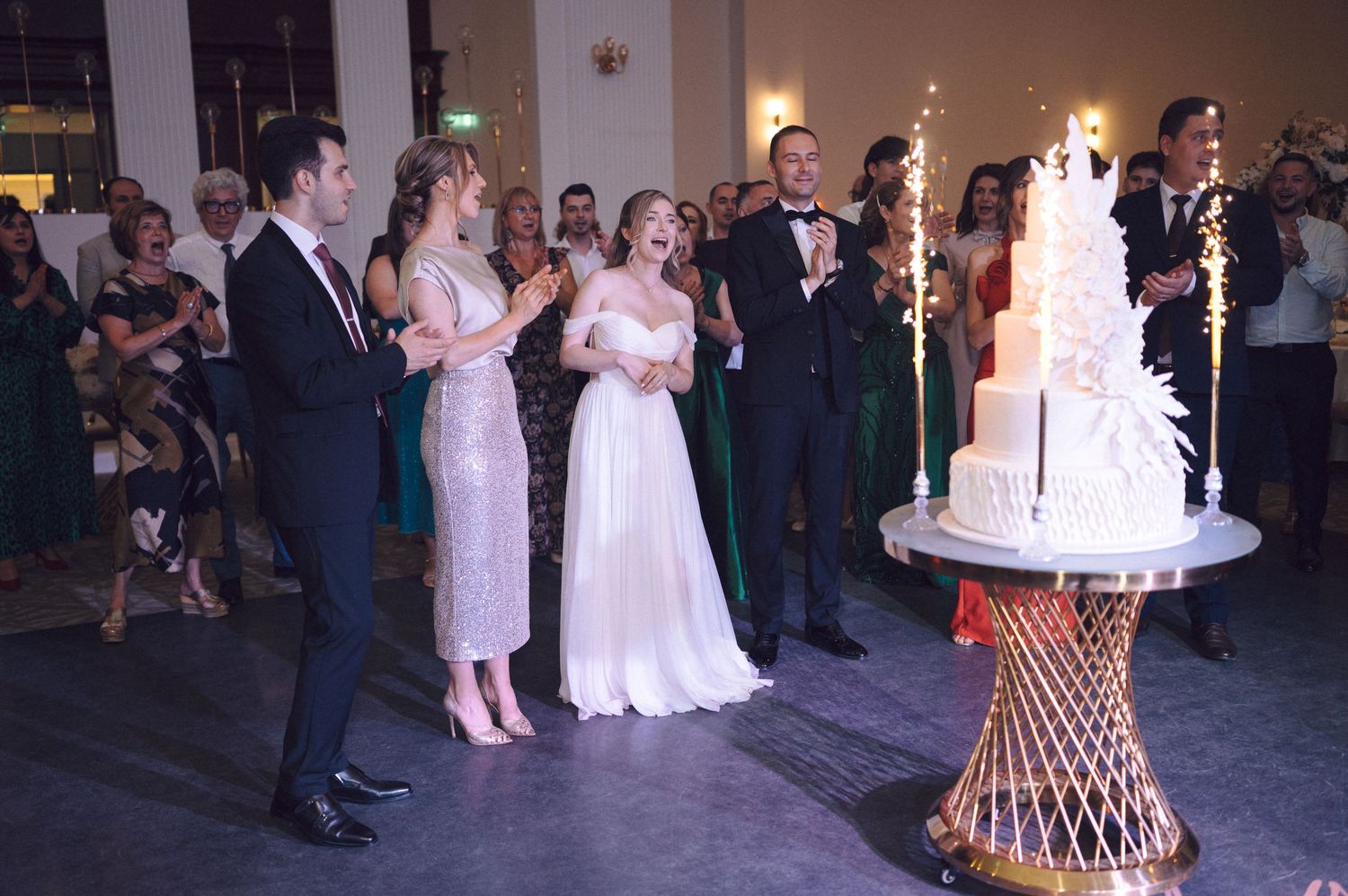 Wedding guests gather in a reception hall to celebrate a joyous occasion with dancing, dining and a multi-tiered cake.
