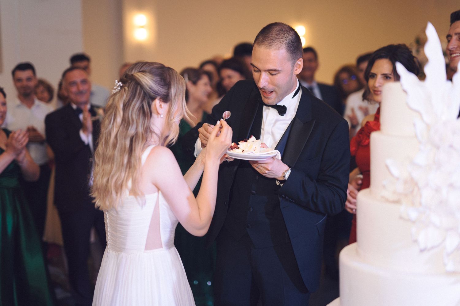Wedding guests dance together on a softly lit dance floor during an evening reception celebration.