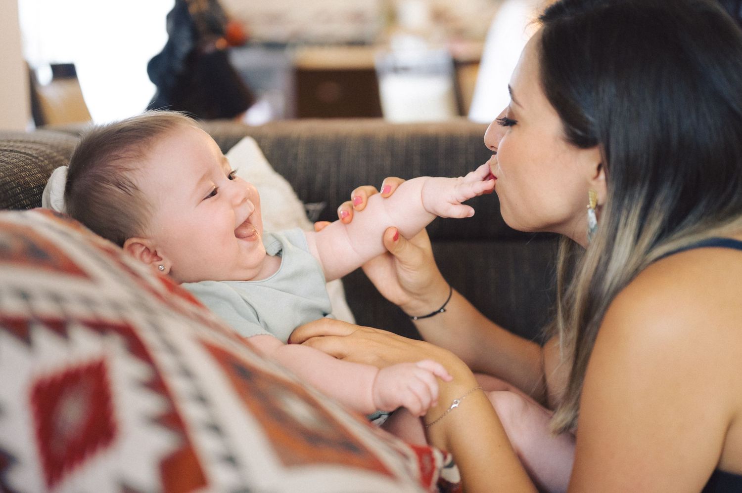 Parent and baby share a tender bonding moment together during playtime with joyful expressions.