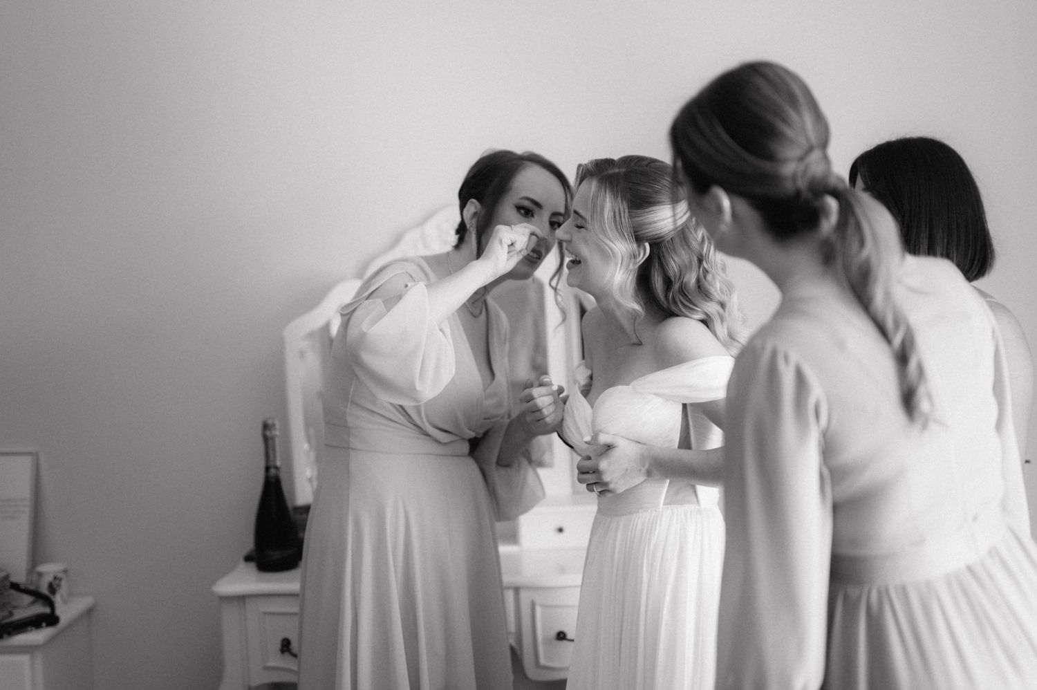 A series of black and white photos showing preparations before a wedding ceremony with bridesmaids in white dresses.