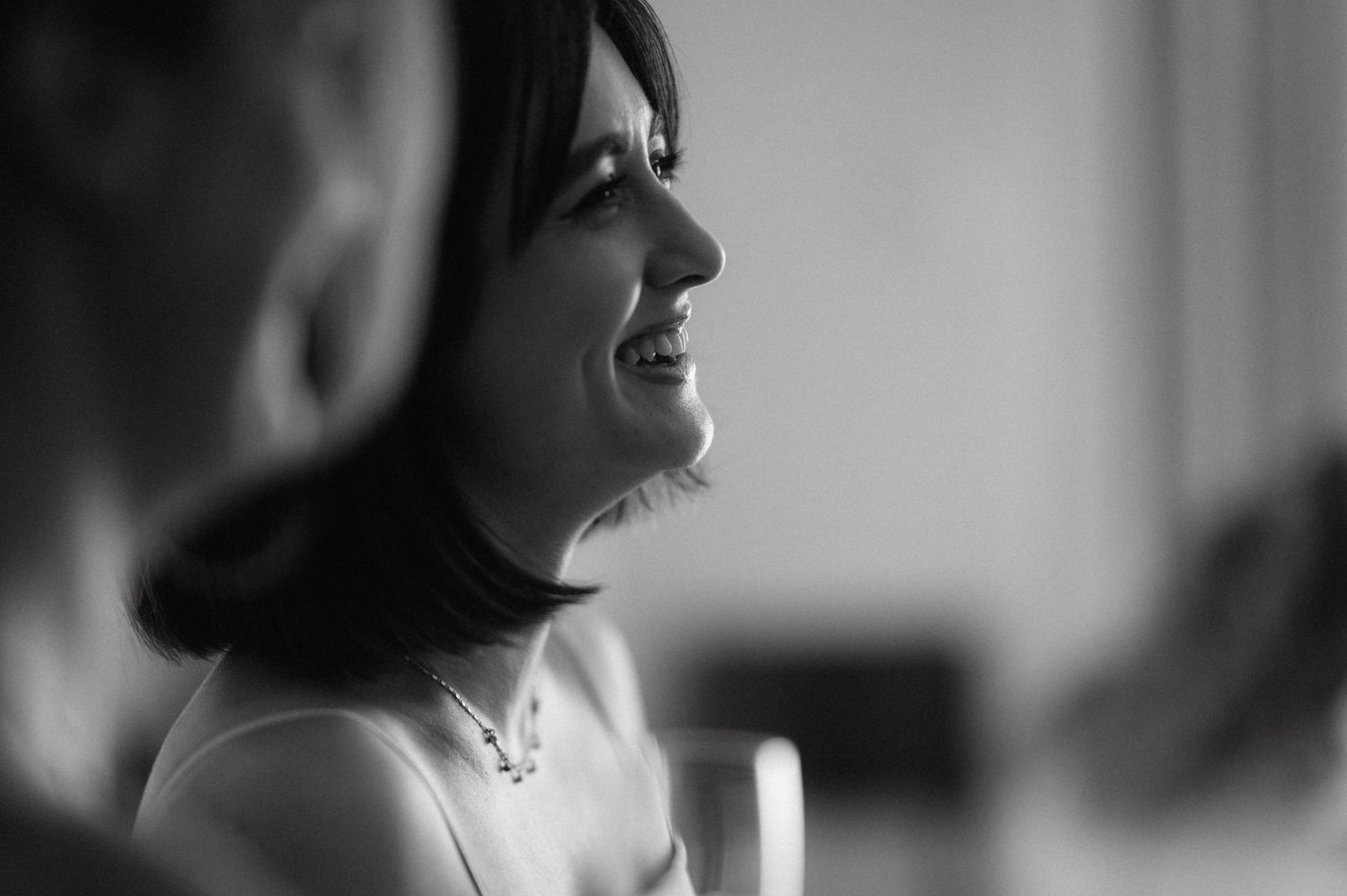 Black and white photograph captures profile view of getting ready moments from a bridal party.