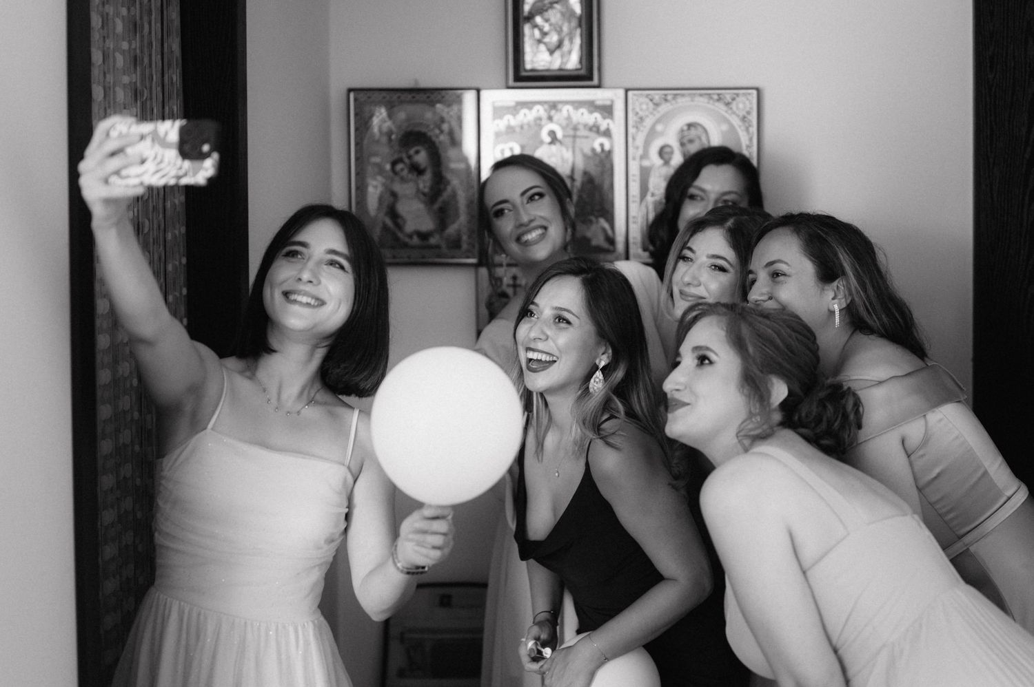 A group of friends posing together with a balloon for a fun black and white selfie moment at a party.