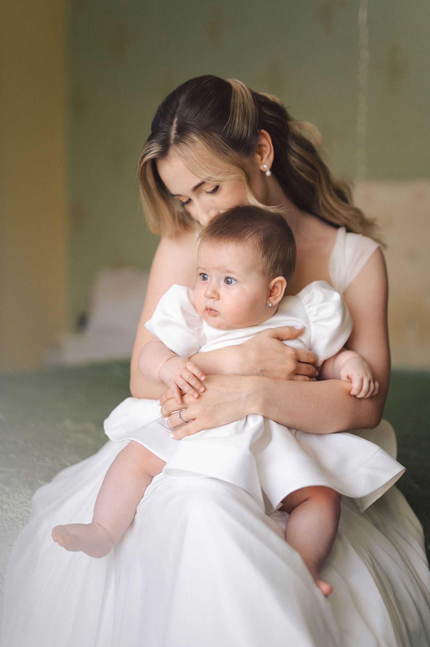 Five sequential photos show a tender moment between parent and child in white clothing on light-colored bedding.