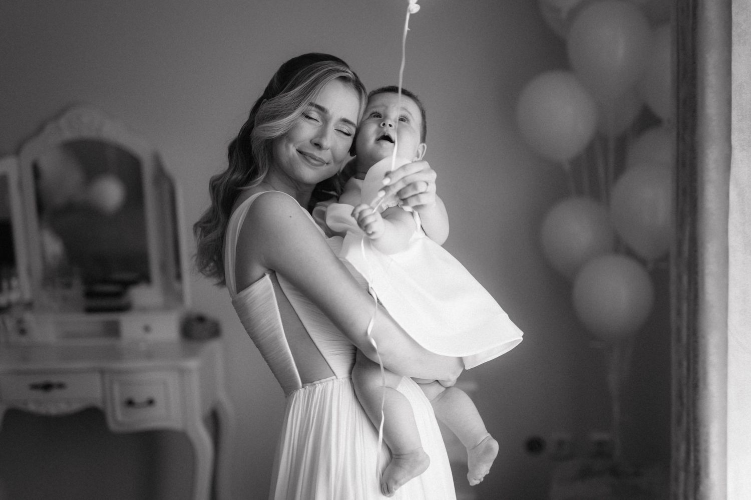 Black and white photo collage showing intimate family moments with newborn baby and parents in various indoor settings.