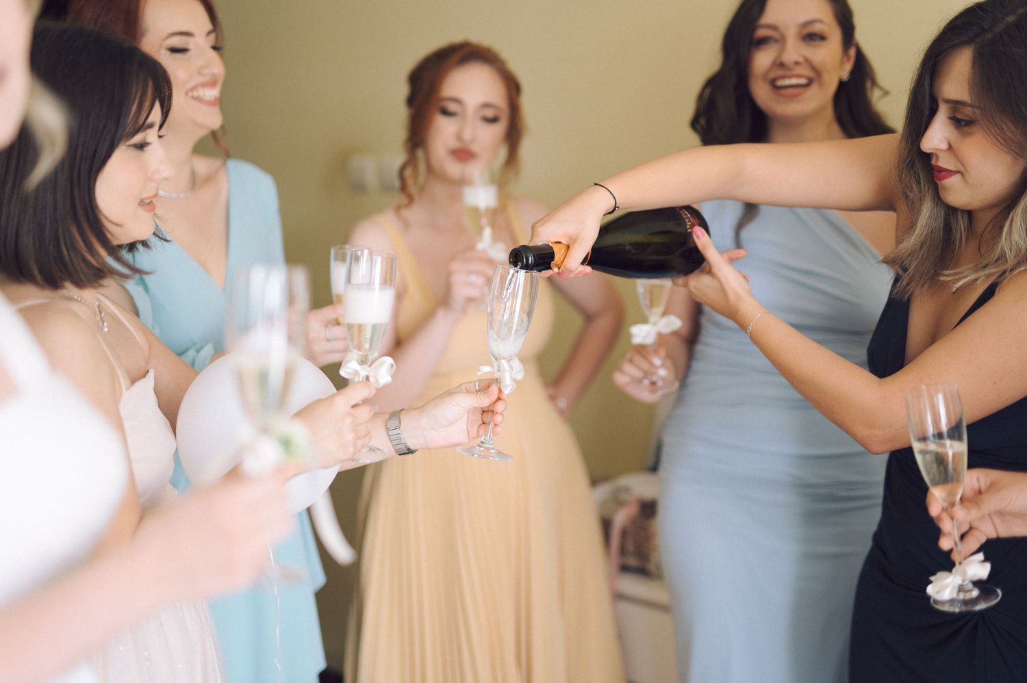 A group of women raise champagne glasses in celebration at a bridal shower event.