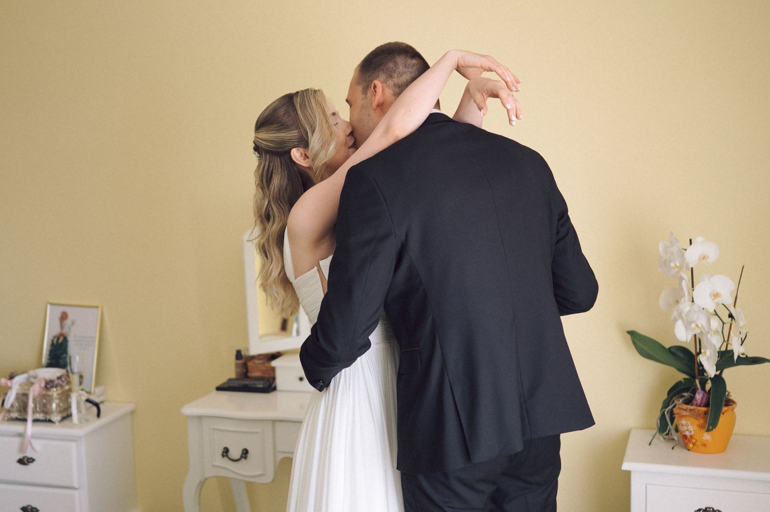 A couple in formal attire embraces during a private moment before a wedding ceremony.