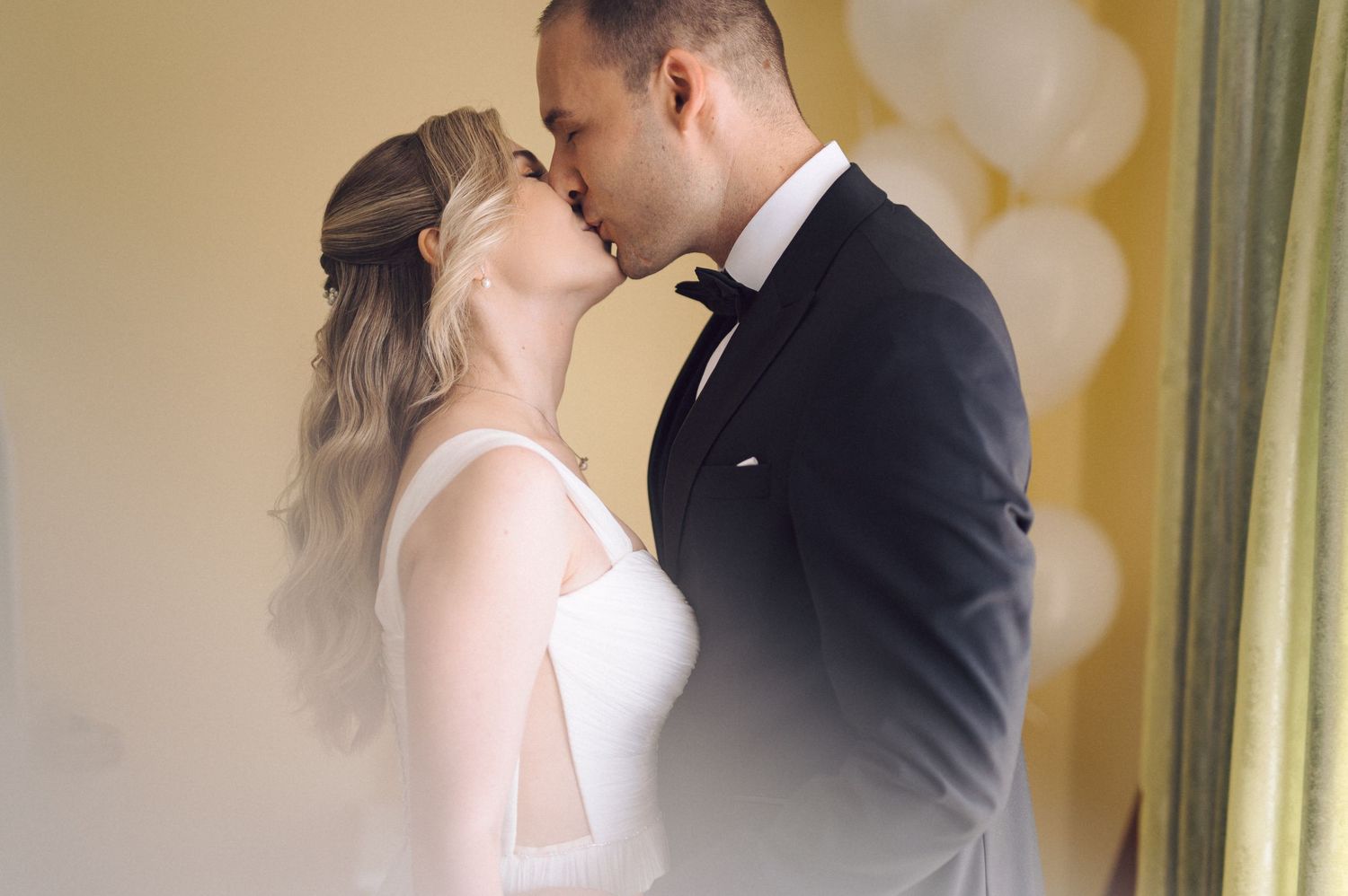 A bride and groom share a romantic moment in front of a golden wall with elegant mirrors.
