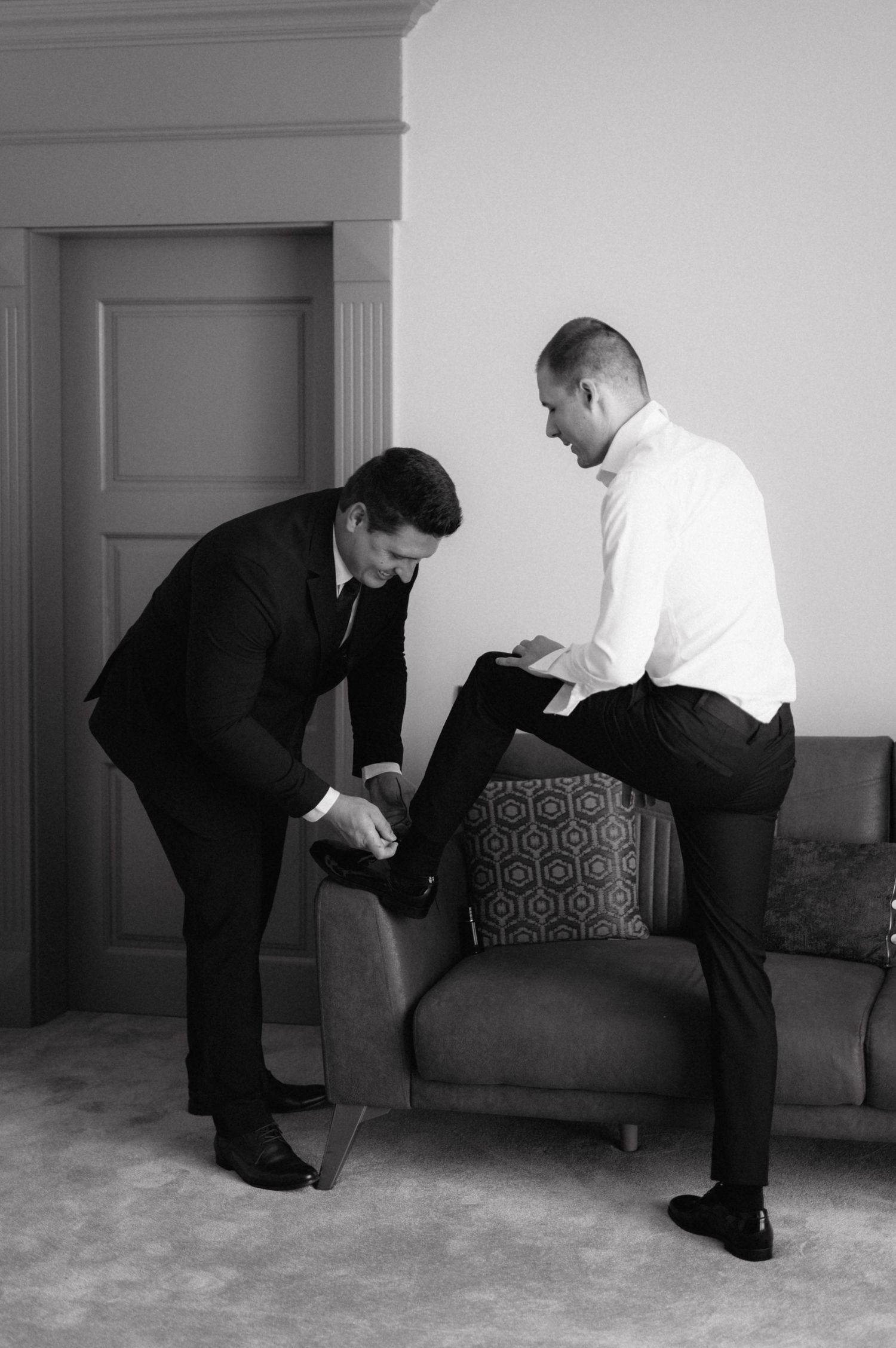 A sequence of black and white photos shows two men in suits demonstrating self-defense techniques on a couch.