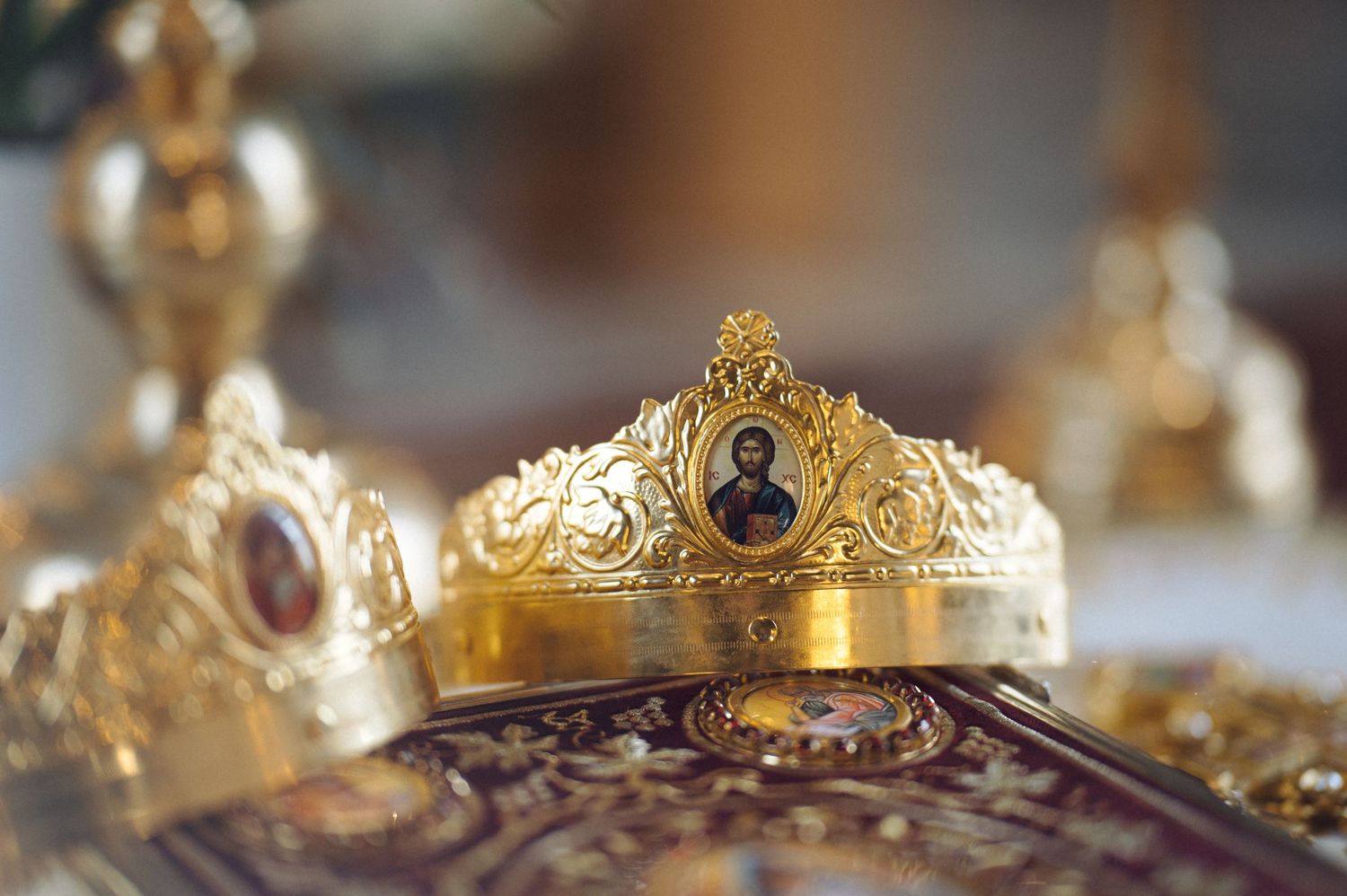Gold ornate crown with intricate filigree design and jewel details displayed against blurred background.