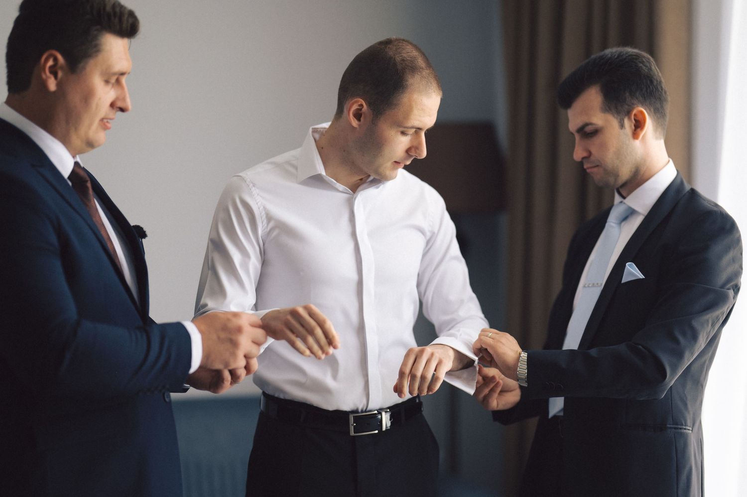 Three professionals in business attire checking their watches while standing in an office setting.
