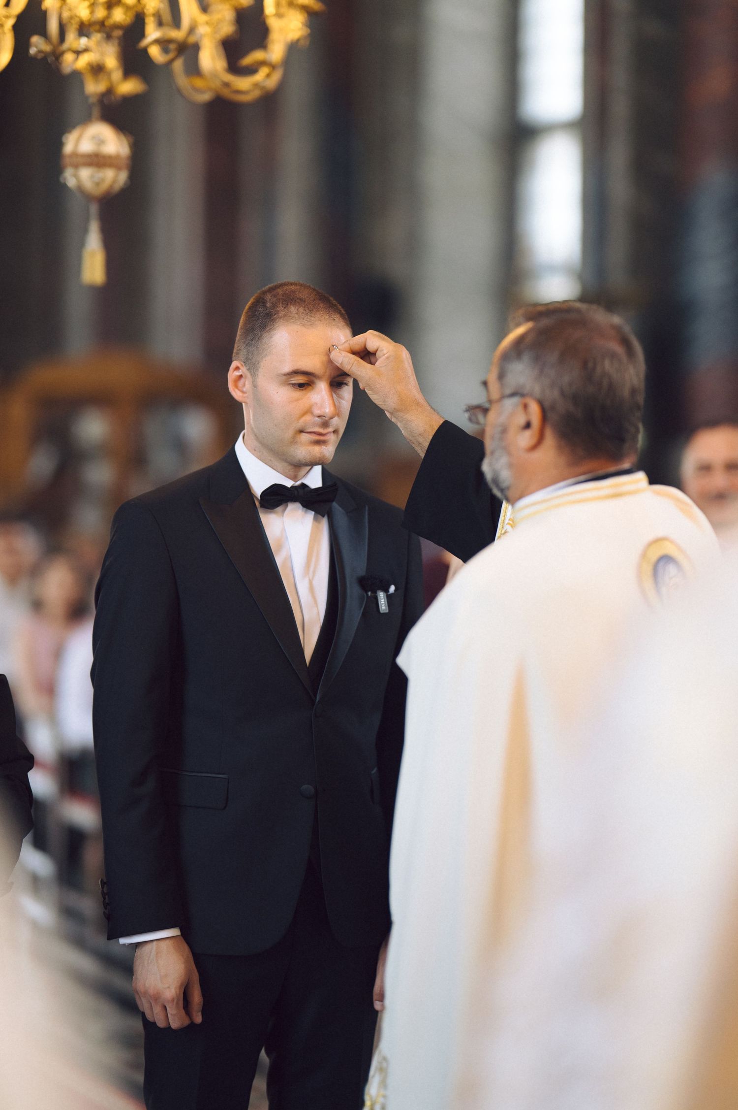 A priest performs the Ash Wednesday ritual during a Catholic service in a traditional church setting.