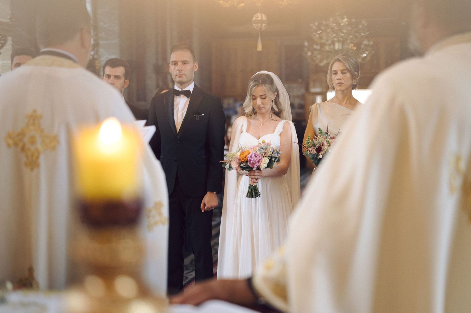 A perfect wedding processional moment captured in an elegant church with soft bokeh lighting and floral decorations.