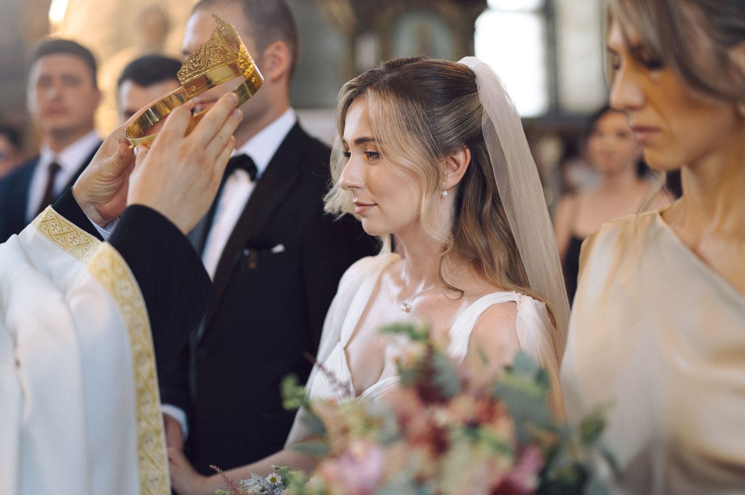 Wedding guests raise their champagne glasses during a joyous toast at an elegant indoor reception celebration.