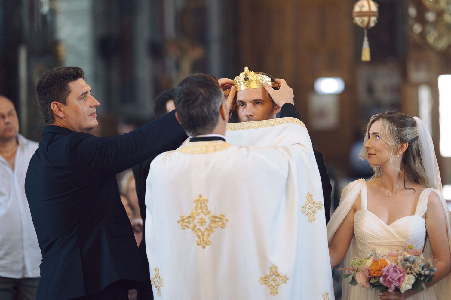 Elegant church wedding ceremony with bride and groom at the altar surrounded by floral decorations and candles.