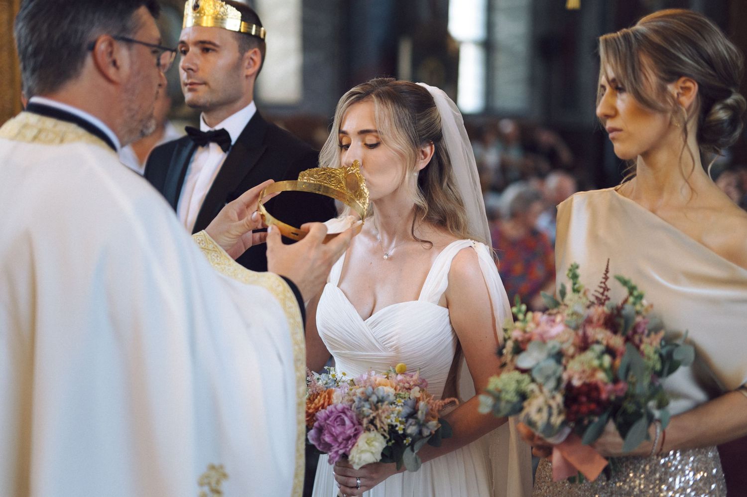 A bride takes communion during a traditional Catholic wedding ceremony while holding a colorful floral bouquet.