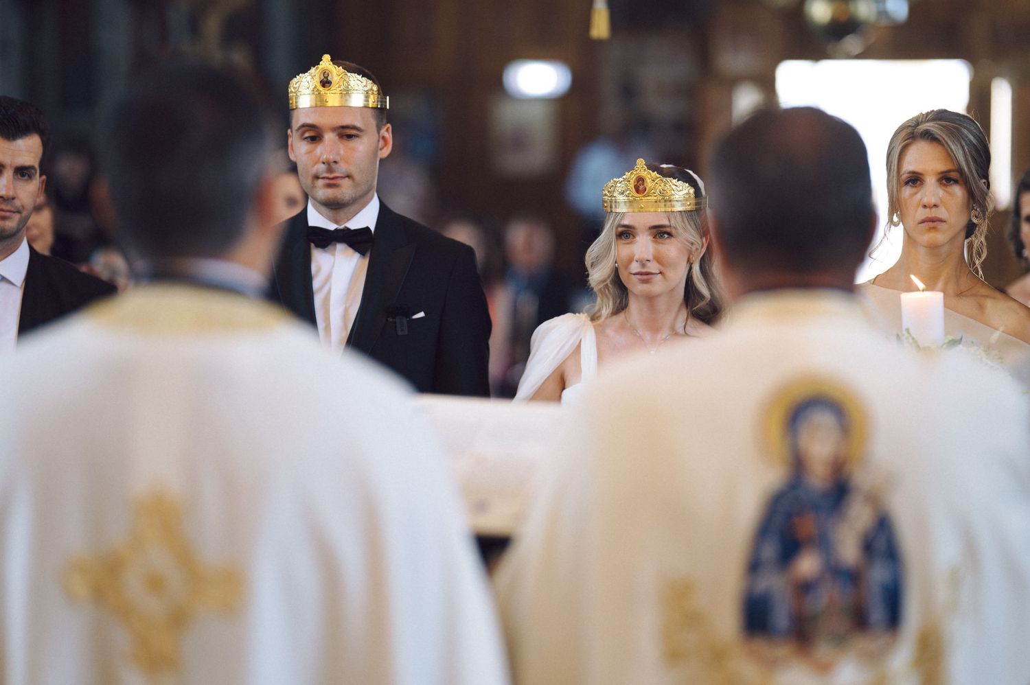 Orthodox wedding ceremony shows a couple wearing golden crowns during their traditional religious service in a church.