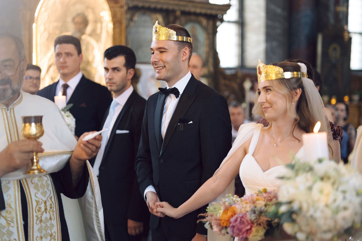 Wedding ceremony in a church with the couple wearing traditional gold crowns during an Orthodox Christian service.