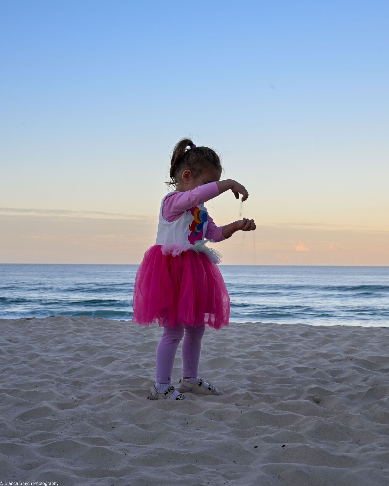 A little girl playing with sand on the beach