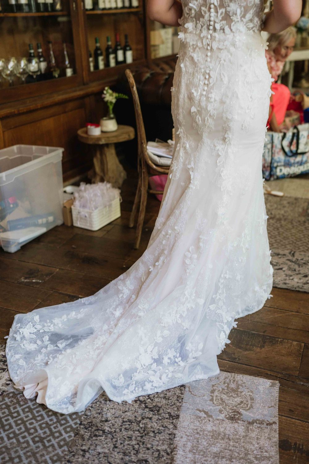 Detail shot of white lace wedding dress train on vintage wooden floor.