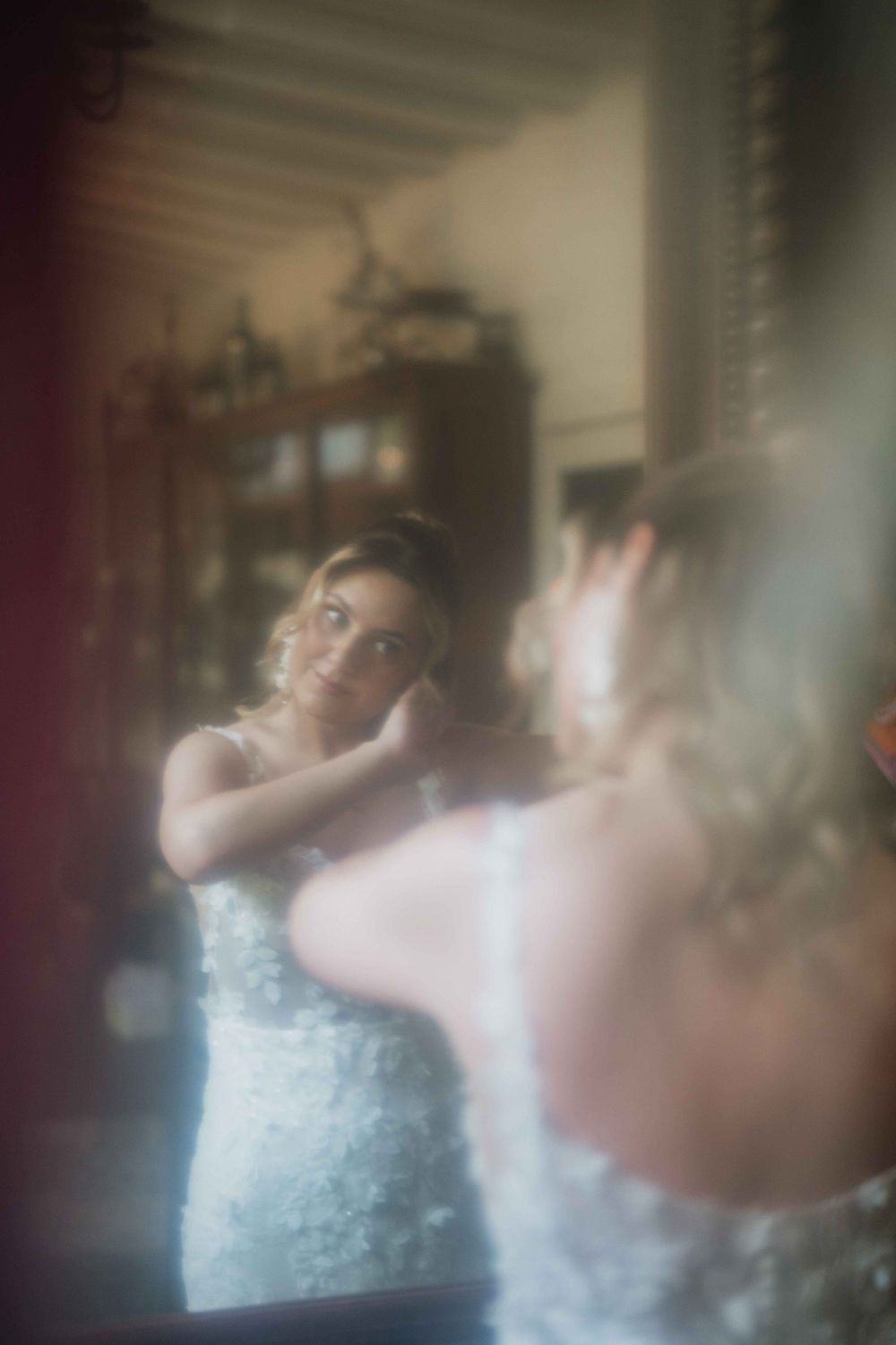 Dreamy soft-focus reflection of bride in vintage mirror with ornate details.