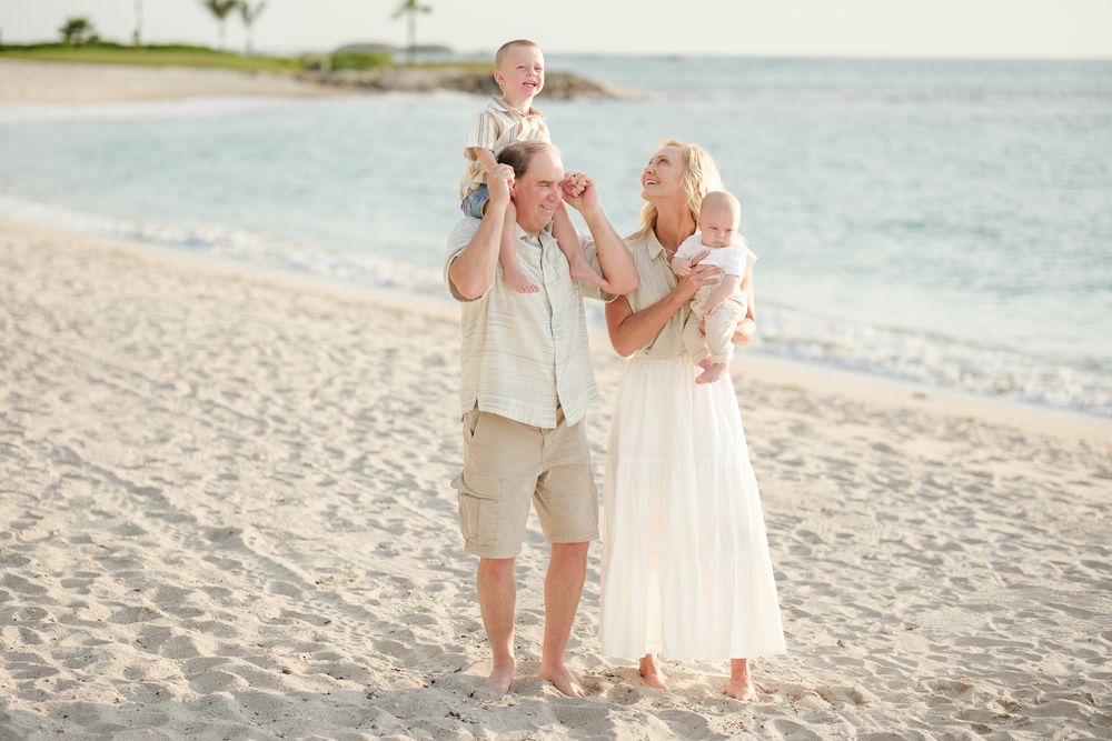 Group shares joyful moments while walking on sandy beach at sunset wearing light colored casual attire.