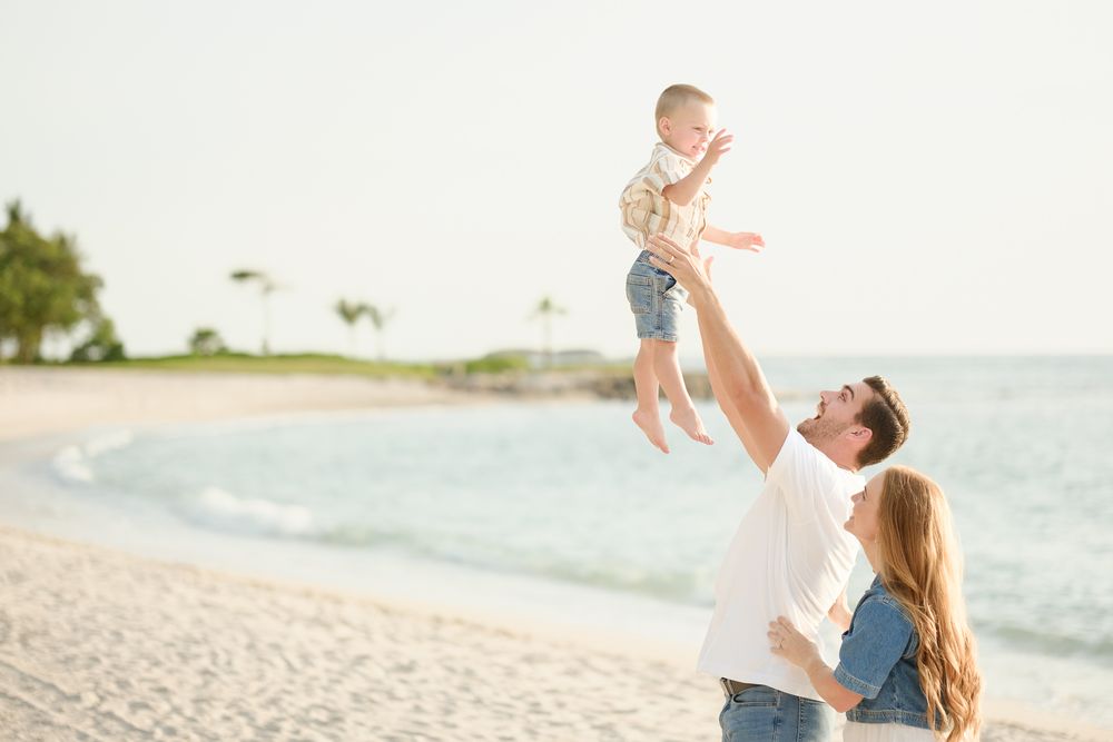 A family plays together on a scenic beach as golden sunlight illuminates the shoreline.