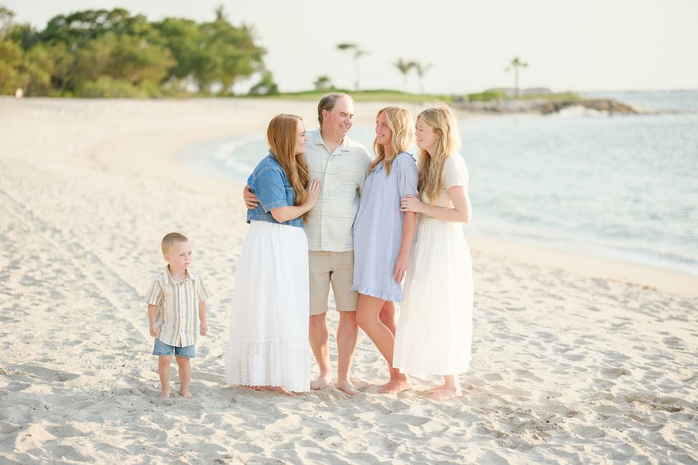 A family enjoys a relaxing evening walk together along a tropical beach with white sand and gentle waves.