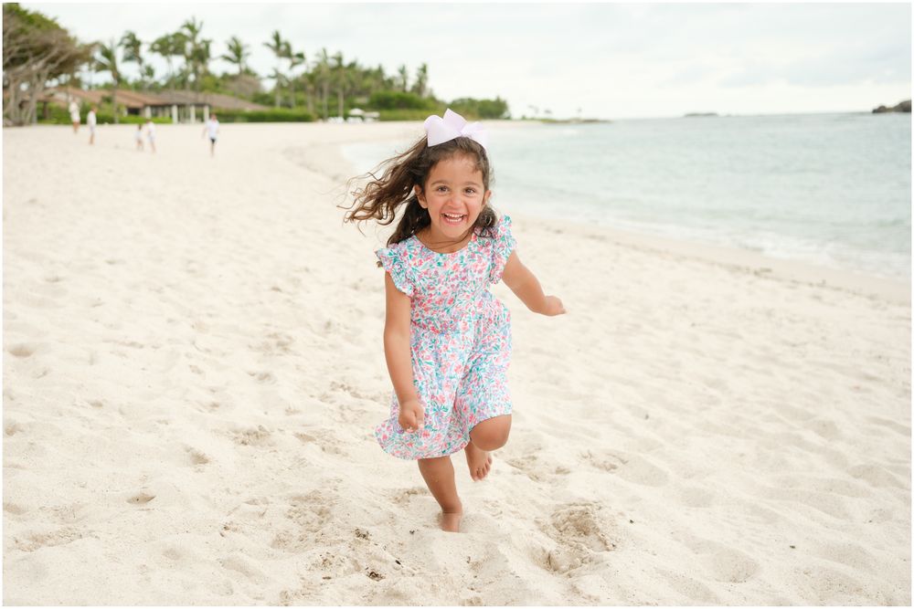A joyful young figure dances and plays on a pristine white sandy beach near tropical blue ocean waters.