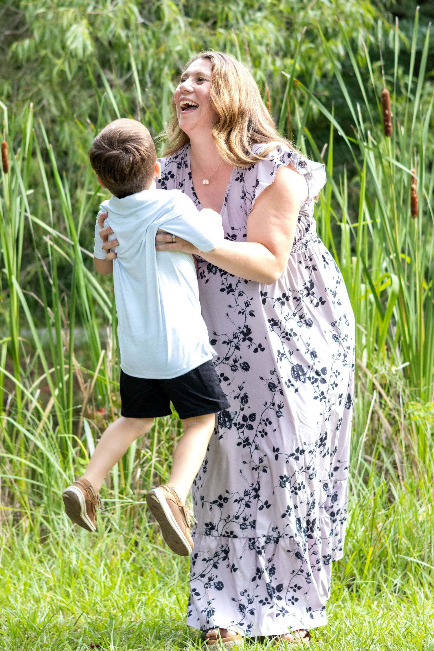 People in floral dresses having fun outdoors against tall green reeds and grass.