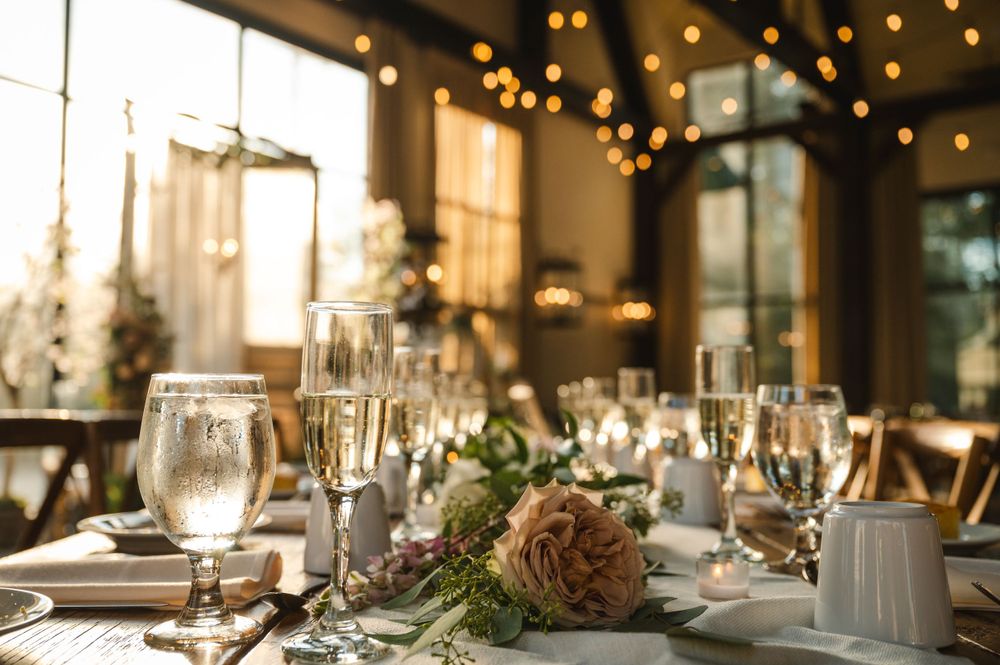 Elegant barn wedding reception setting with champagne glasses, candles and floral decorations under warm lights at the Barn at Villa Venezia