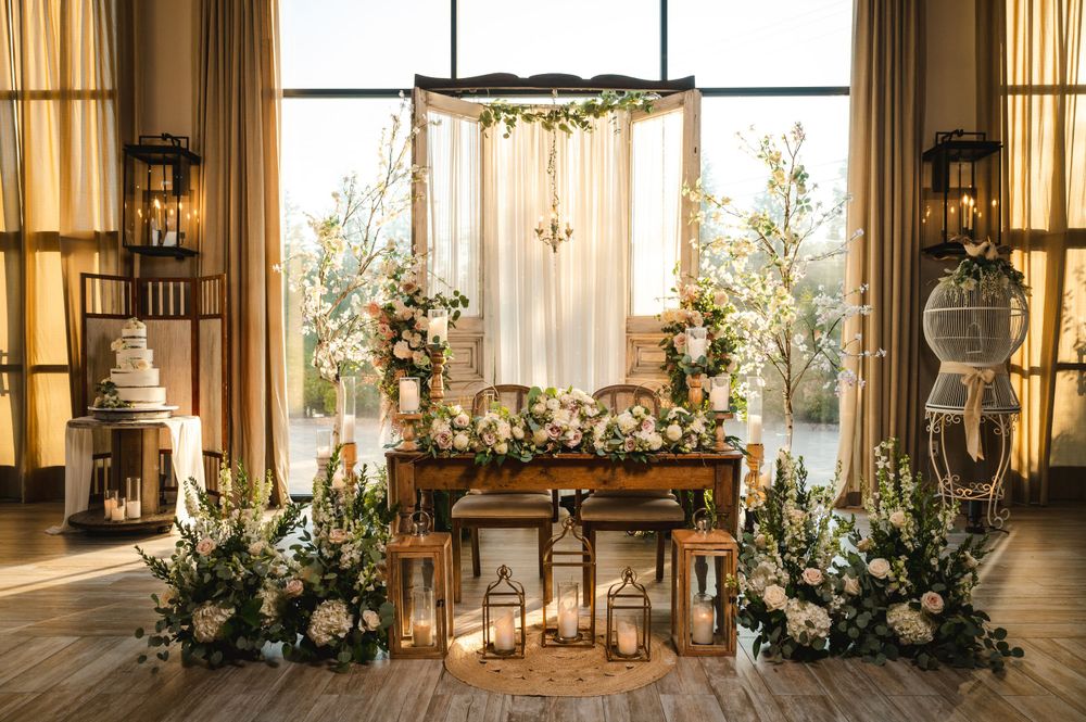 Rustic wedding ceremony sweetheart table setup with wooden table, floral arrangements and greenery at The Barn at Villa Venezia Middletown.