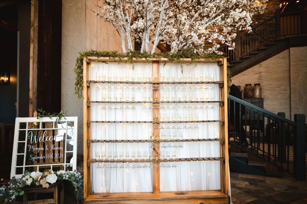 Champagne wall next to welcome sign in elegant entryway with rustic staircase at The Barn at Villa Venezia Middletown, NY.