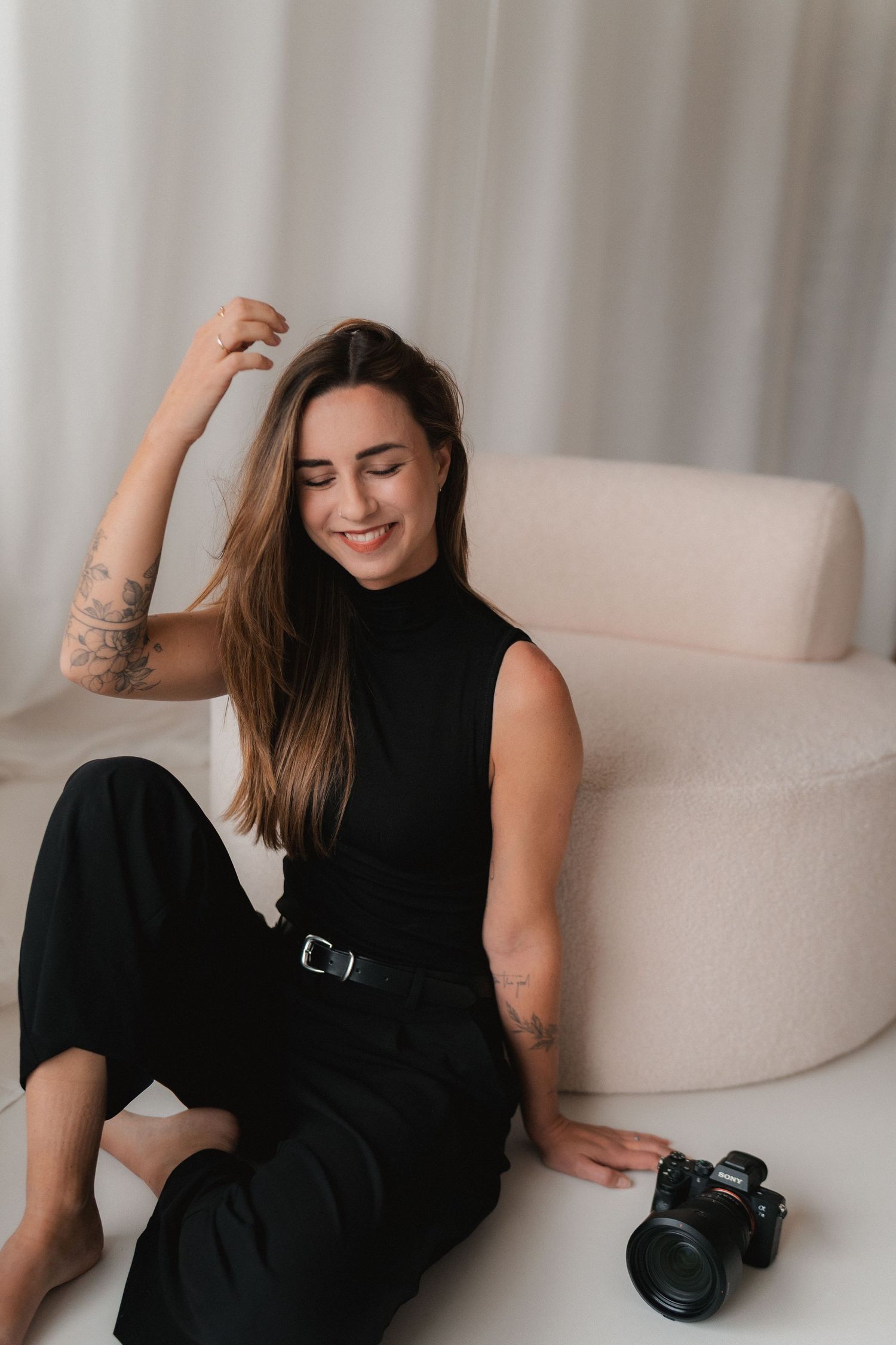 Die Fotografin Alina sitzt entspannt in ihrem Studio und stützt den Kopf auf ihre Hand