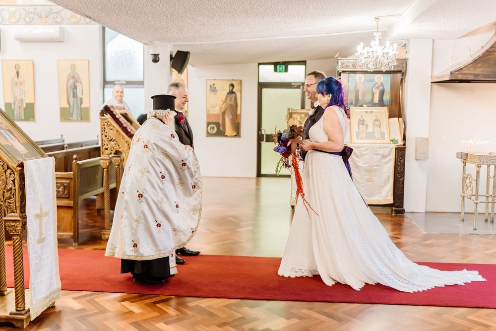 A traditional Orthodox Christian wedding ceremony taking place inside a church with priests and flowing white dress.