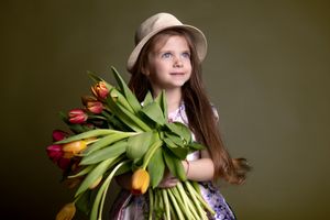 Person with long hair holding tulips and greenery in vintage-inspired spring portrait.