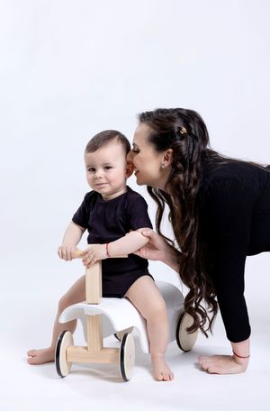 Young child plays on wooden stool during professional photo session on white background.