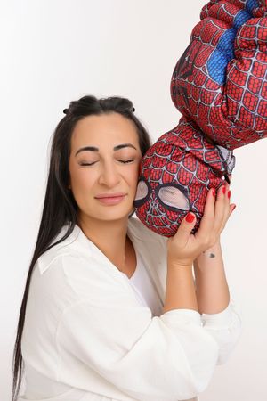 Woman with closed eyes hugging a Spider-Man stuffed toy against a white background.